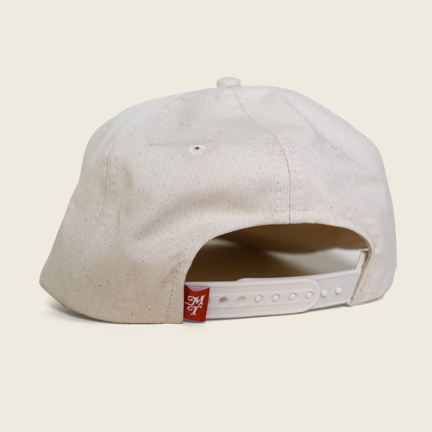 Natural cap with a brand logo on the back against a beige background
