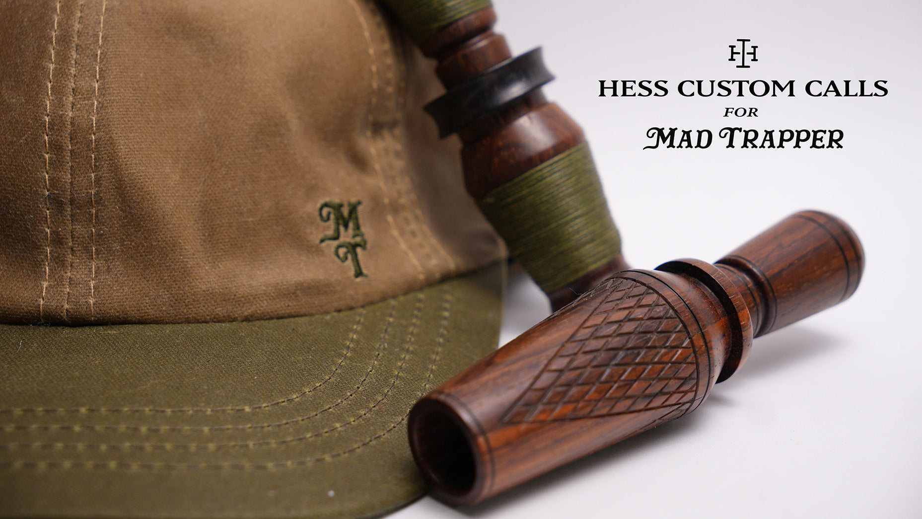 Wooden hunting call with a brown cap featuring a logo on a white background, branded 'Hess Custom Calls for Mad Trapper'.