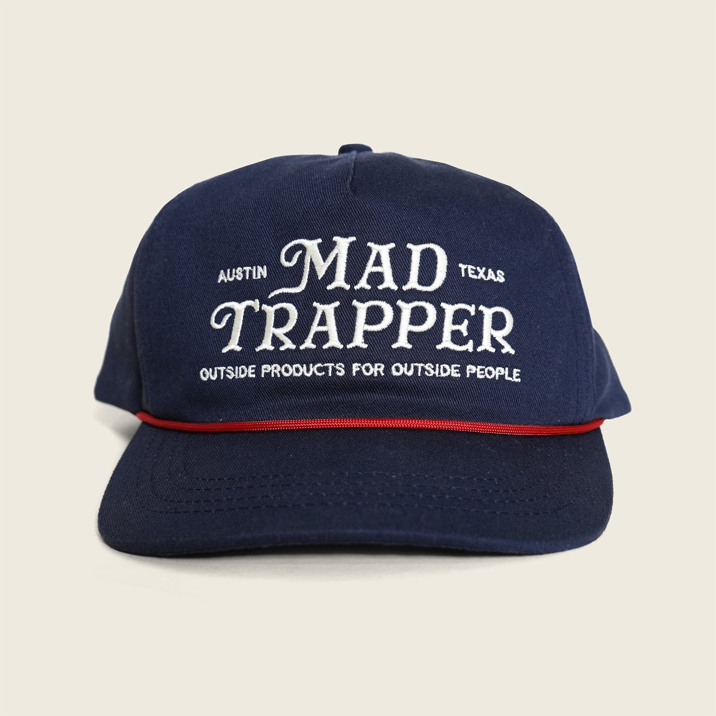 Navy blue cap with 'Mad Trapper' text on a beige background