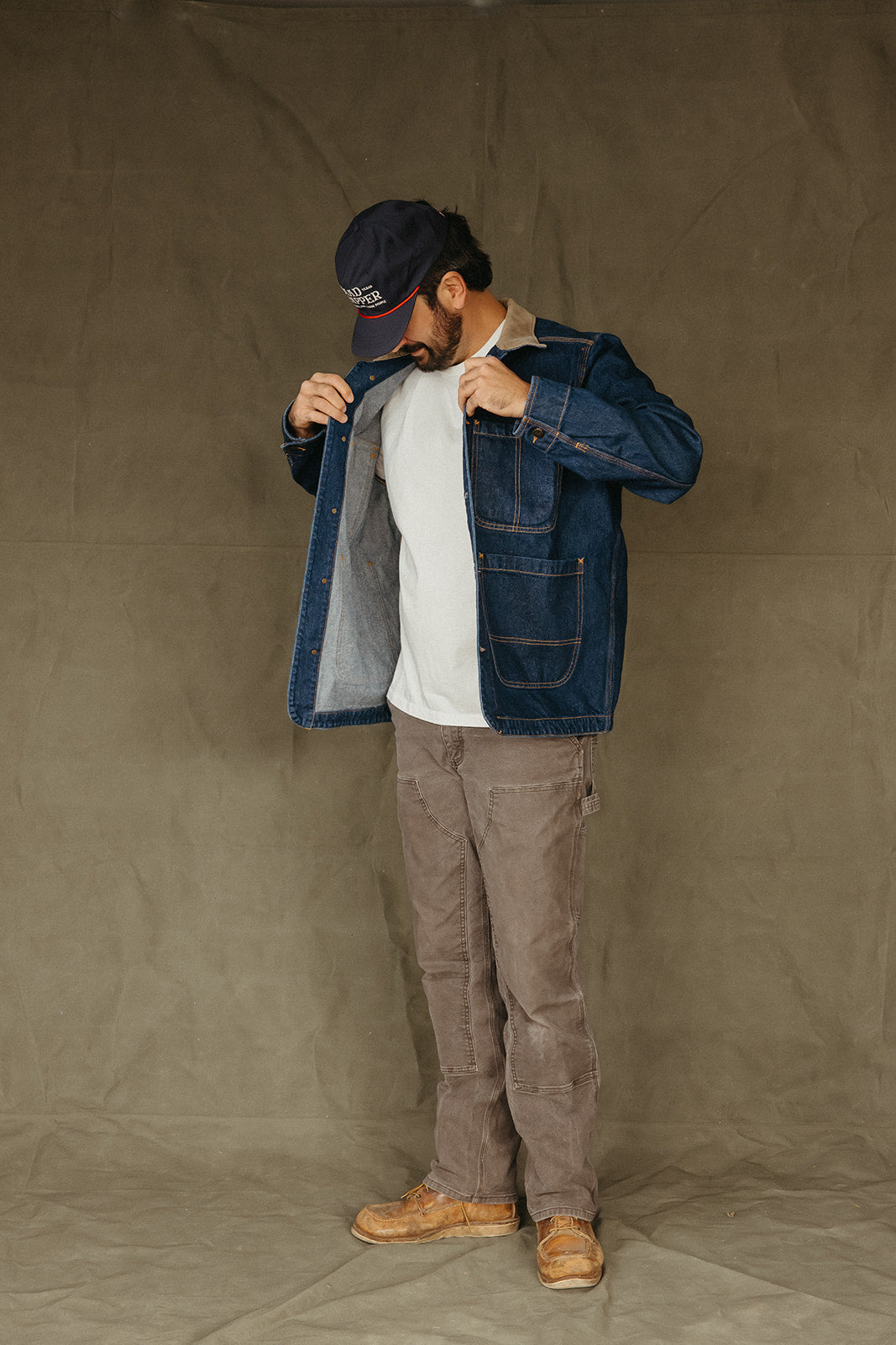 Person wearing a Mad Trapper Denim Field Coat, white shirt, brown pants, and brown shoes against a plain background